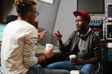 Young rapper explaining deejay which type of sound recording he wants to be produced