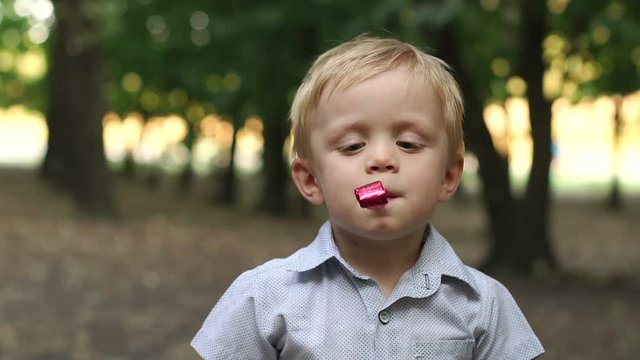 Happy little boy are blowing into unfolding tube at a birthday party. Little boy having fun and blows a party horn. Little boy with birthday pipes.