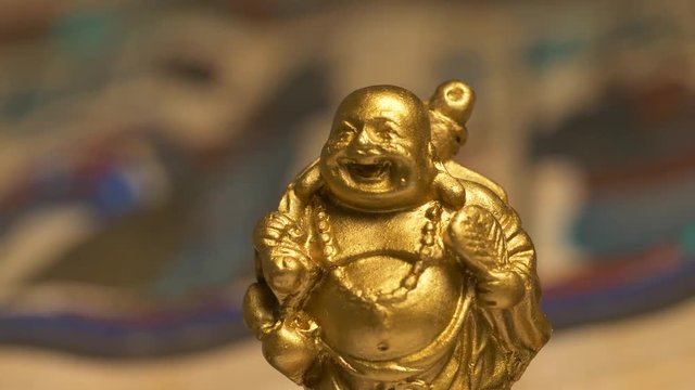 Camera turning around a laughing Buddha golden statue