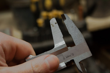 Marco focus is set to the caliper that the man is holding in his hand. Workshop and tools in the...