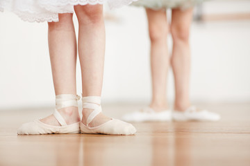 Obraz premium Feet of little ballerina in pointes on the floor during ballet training