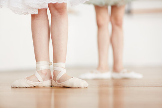 Feet of little ballerina in pointes on the floor during ballet training