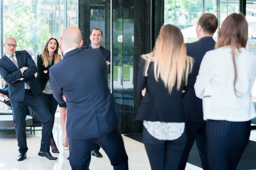 Fototapeta premium Group of business people with businessman leader. Photo from behind with reflection on mirror window.