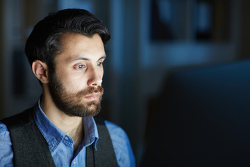 Obraz premium Serious employee working overtime while sitting in front of computer in the night