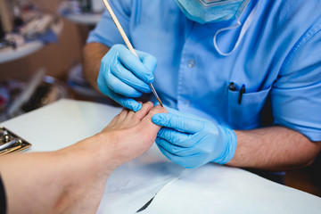 Doctor specialist giving pedicure treatment to his patient. 