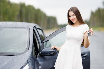 Happy woman driver showing car keys outdoor