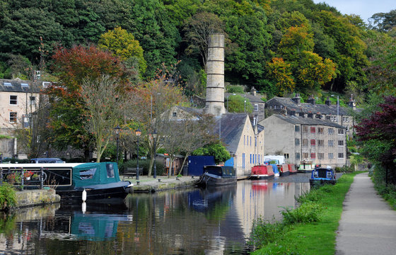 the canal and marina in hebden bridge with boats on the water, towpath and surrounding hillside trees