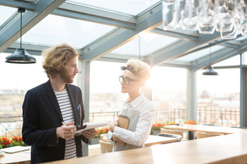 Young waitress listening to her employer during discussion of her working duties