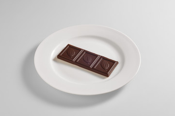 Round dish with a bar of dark chocolate