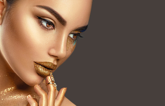 Fototapeta Fashion art makeup. Portrait of beauty woman with golden skin. Glamour shiny professional makeup