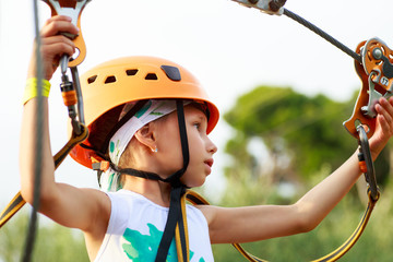 Cute  girl enjoying a sunny day in a climbing adventure activity park.  girlat climbing activity in high wire forest park.