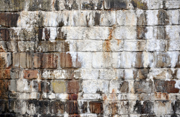 old streaked stone wall with damp stains and white encrusted surface