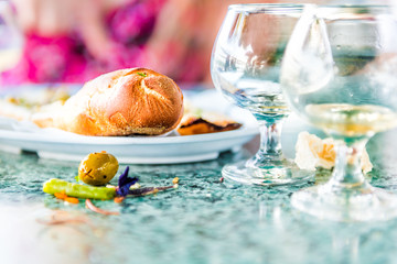 Closeup of leftovers in restaurant on table with small glass cognac whiskey rum glasses and messy dirty surface, bread