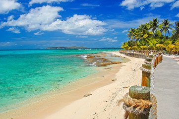 Coastal walkway along beautiful sandy tropical beach on Palm island, Caribbean Sea region, Lesser Antilles