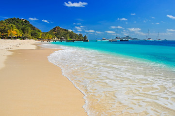 Wonderful tropical beach with boats in distance, Palm island, Caribbean region of Lesser Antilles
