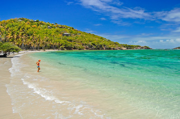Woman entering water on secluded beach of Spring bay on Bequia Island, Caribbean Sea region of...