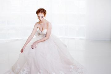 Portrait of a beautiful girl in a wedding dress. Bride in luxurious dress sitting on a chair