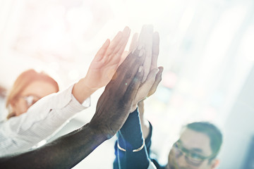 Smiling diverse businesspeople high fiving together in a modern office