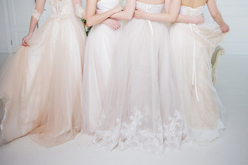 Fototapeta na wymiar Bride in wedding salon. Four beautiful girl are in each other's arms. Back, close-up lace skirts