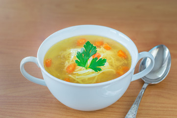 Traditional Polish chicken broth with carrot parsley and spoon.
