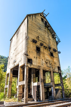 Abandoned retro vintage concrete loading receiving terminal building exterior in Thurmond, West Virginia ghost town with decaying structure walls, windows, railroad