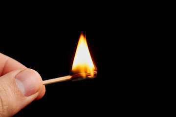 Matchstick in hand isolated on black background