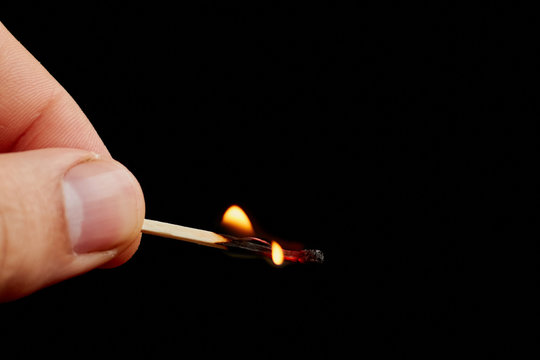 Matchstick in hand isolated on black background
