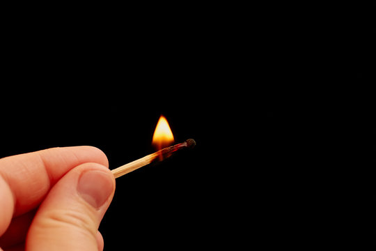 Matchstick in hand isolated on black background