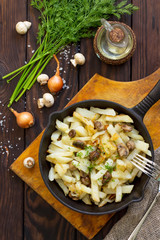 Fried potatoes with champignons mushrooms on the rustic kitchen table. Flat lay. Top view.