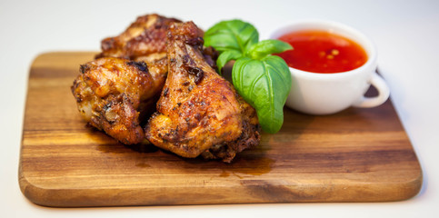 Chicken wings with sweet chilli sauce on the wooden cutting board