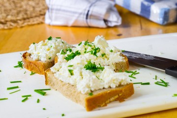 Three sliced bread with curd cheese and chive, knofe and towel.