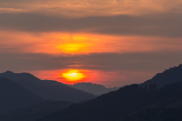 Obraz premium Beautiful landscape of a big setting sun over the silhouette of the mountains, Salciua, Romania