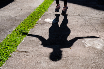 shadow of woman with black clothing jumping rope in the park