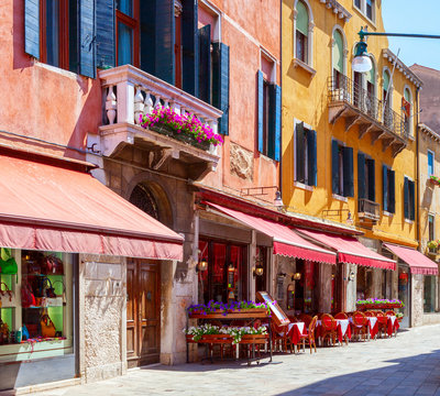 Fototapeta Colorful  street with tables of cafe at  a sunny morning, Venice, Italy.