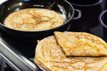 Pancakes for carnival are baked in a frying pan, on a plate