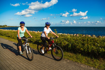 Fototapeta premium Women riding bicycles at seaside