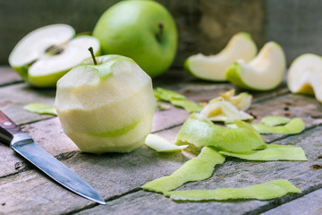 Fototapeta na wymiar Green peeled apple on natural rustic wooden background.