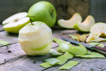 Green peeled apple on natural rustic wooden background.