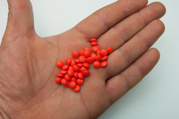 Large red pills are decomposed on the hand of man.