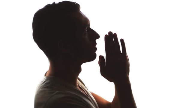 Silhouette of a man hand praying, close up