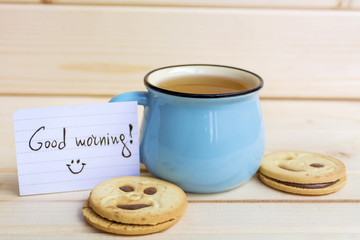blue mug of tea and oatmeal cookies on wooden background