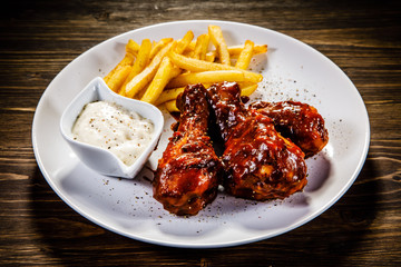 Barbecued drumstick with french fries on wooden table