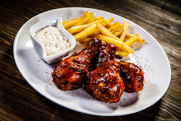 Barbecued drumstick with french fries on wooden table