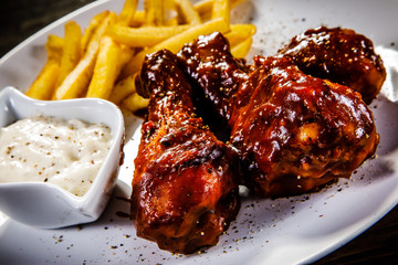 Barbecued drumstick with french fries on wooden table