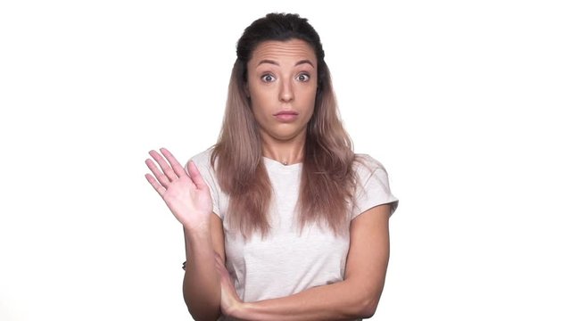 Portrait of caucasian determined woman expressing perplexity and confusion with showing stop gestures, over white background slow motion. Concept of emotions