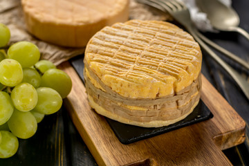 Tasting of oldest french AOC soft pudgent wrapped yellow cheese Livarot from Normandy, french cheese