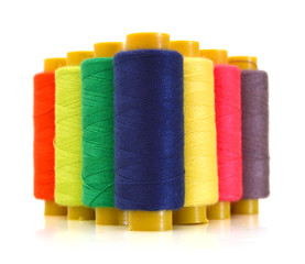 Pyramid of many-coloured bobbins of thread isolated on white