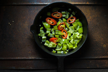 Green pepper and chili on a cast-iron frying pan copy space