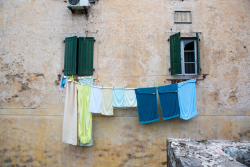 multi-colored linen is dried outside the window of an old house