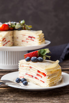 Crepe cake bakery piece with strawberry and vanilla sauce on wood table. Maslenitsa, traditional Russian holiday